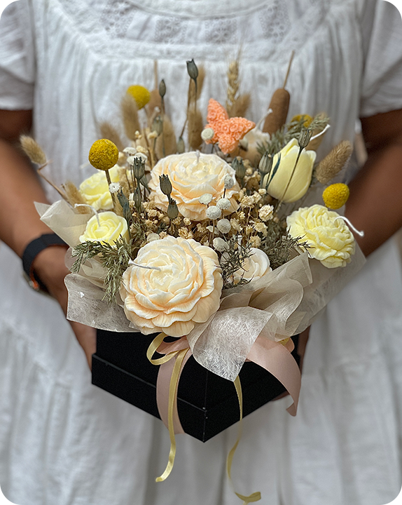 Person holding cream and yellow flower arrangement